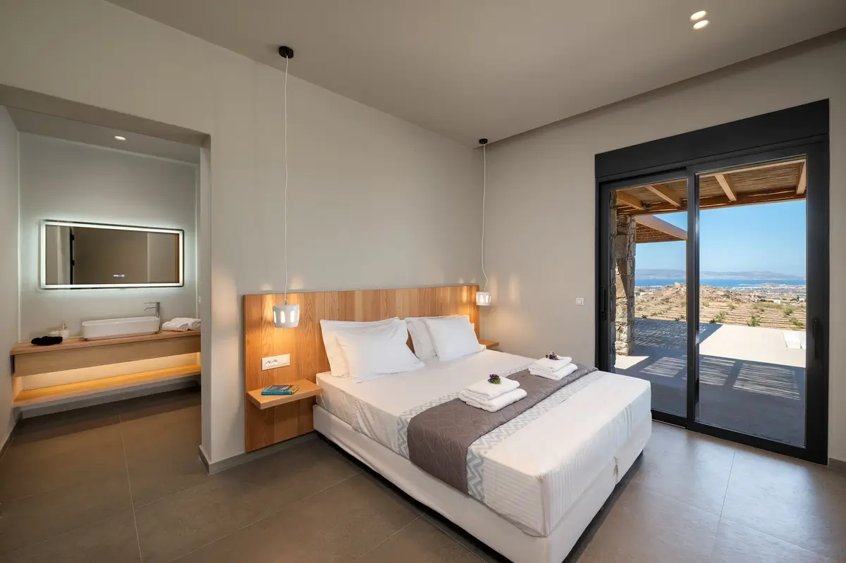 Large bedroom showcasing the bed, bathroom and view outisde